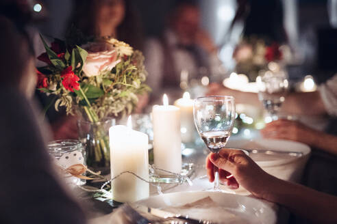 Ein Mittelteil einer Familie, die auf einer Indoor-Geburtstagsfeier an einem Tisch sitzt und Gläser hält. - HPIF17551