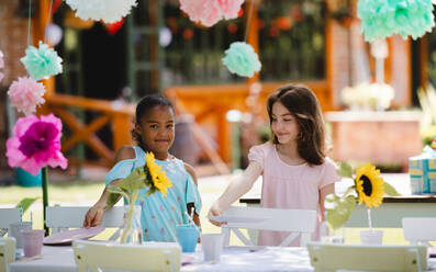 Fröhliche kleine Mädchen decken den Tisch für die Sommergartenparty, Geburtstagsfeier Konzept. - HPIF17561