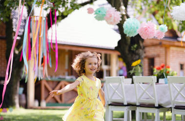 Kleines Mädchen läuft im Freien im Garten im Sommer, eine Geburtstagsfeier Konzept. - HPIF17569