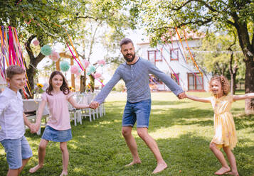 Mann mit Gruppe von Kindern auf Geburtstagsparty spielen im Freien im Garten im Sommer, Feier-Konzept. - HPIF17574
