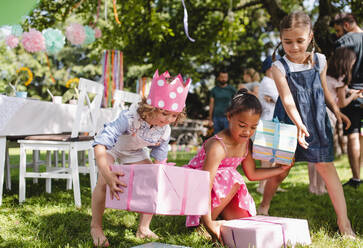 Gruppe von kleinen Mädchen mit Geschenken im Garten im Sommer, die spielen. - HPIF17617