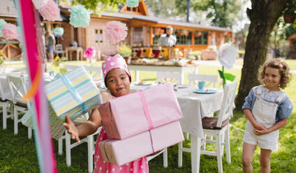 Porträt eines kleinen Mädchens mit vielen Geschenken im Garten im Sommer. - HPIF17619