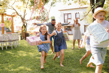 Kleine Kinder ruunning mit Geschenk im Freien im Garten auf Geburtstagsparty, spielen. - HPIF17621