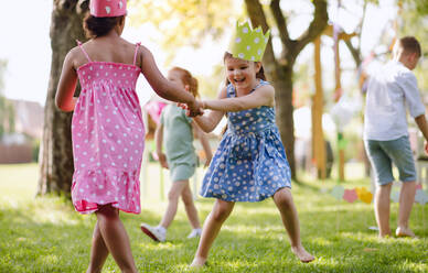 Kleine Kinder, die im Sommer draußen im Garten stehen und spielen, ein Konzept für ein Fest. - HPIF17622