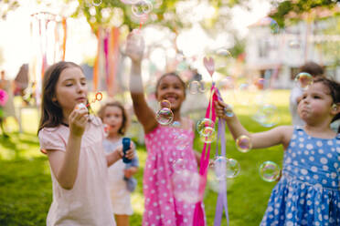 Kleine Kinder, die im Sommer draußen im Garten stehen und spielen, ein Konzept für ein Fest. - HPIF17624