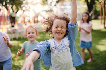 Kleine Kinder, die im Sommer draußen im Garten stehen und spielen, ein Konzept für ein Fest. - HPIF17628