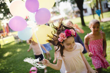 Kleine Kinder, die im Sommer draußen im Garten rennen und spielen - ein Konzept für ein Fest. - HPIF17637