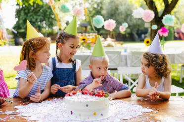 Down-Syndrom-Kind mit Freunden auf Geburtstagsfeier im Freien im Garten im Sommer. - HPIF17649