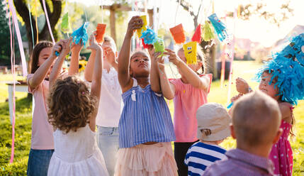 Kleine Kinder, die im Sommer draußen im Garten stehen und spielen, ein Konzept für ein Fest. - HPIF17667