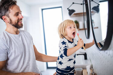 Mature father with small son indoors in bathroom, brushing teeth in the morning or evening. - HPIF17743