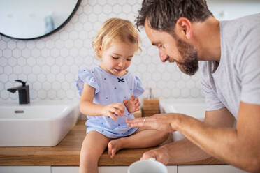 Reifer Vater mit kleinem Mädchen drinnen im Badezimmer, Nägel lackieren. - HPIF17749