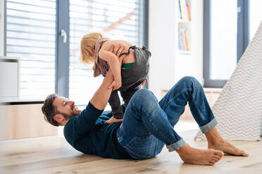 Reifer Vater mit kleinem Jungen spielt drinnen im Schlafzimmer und hat Spaß. - HPIF17756