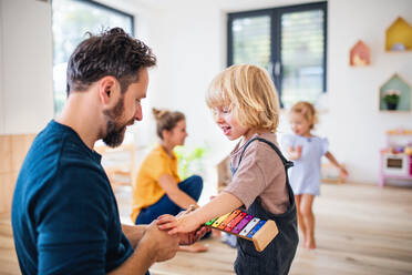 Junge Familie mit zwei kleinen Kindern, die im Schlafzimmer spielen. - HPIF17757