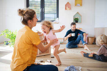 Young family with two small children indoors in bedroom, playing. - HPIF17758