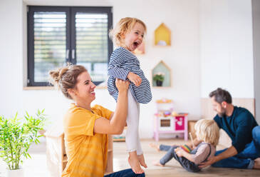 Young family with two small children indoors in bedroom, having fun. - HPIF17761