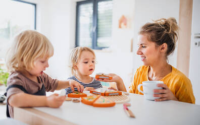 Mother with two small children indoors in bedroom playing with wooden toys. - HPIF17765