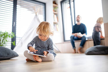 A cute small toddler girl standing indoors in bedroom playing with tablet. - HPIF17771