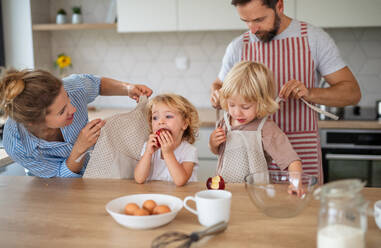 Vorderansicht einer jungen Familie mit zwei kleinen Kindern in der Küche beim Kochen. - HPIF17775