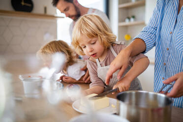 A young family with two small children indoors in kitchen, preparing food. - HPIF17776