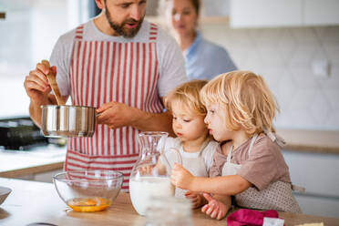 Eine junge Familie mit zwei kleinen Kindern steht in der Küche und kocht. - HPIF17779