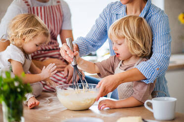 Eine junge Familie mit zwei kleinen Kindern steht in der Küche und kocht. - HPIF17785