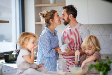 Vorderansicht einer jungen Familie mit zwei kleinen Kindern in der Küche beim Kochen. - HPIF17790