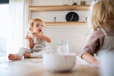 Zwei glückliche kleine Kinder helfen in der Küche beim Kochen. - HPIF17791