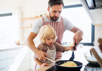 Vorderansicht eines kleinen Jungen mit seinem Vater, der in der Küche Pfannkuchen macht. - HPIF17794