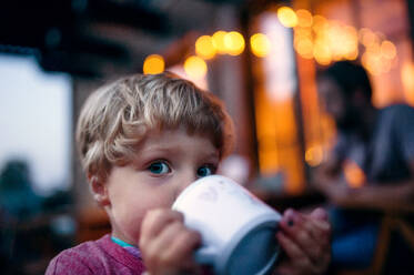 Nahaufnahme eines Kleinkindes, das im Freien steht und aus einer Tasse trinkt. - HPIF17825