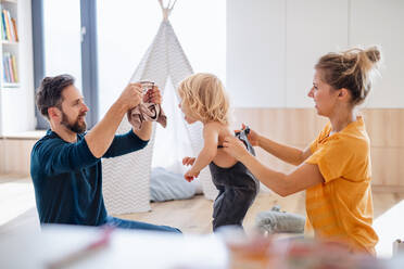 Eine junge Familie mit Kleinkind im Schlafzimmer, die sich anzieht. - HPIF17865