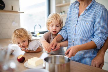 Eine junge Familie mit zwei kleinen Kindern steht in der Küche und bereitet das Essen vor. - HPIF17869