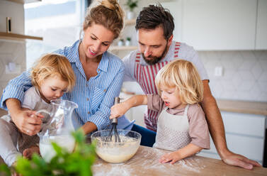Eine junge Familie mit zwei kleinen Kindern steht in der Küche und kocht. - HPIF17872