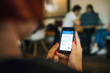 Midsection of unrecognizable woman with smartphone in a cafe, checking finances. - HPIF18003