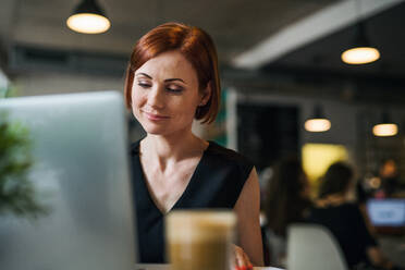 Ein Porträt der attraktiven Frau mit Kaffee sitzt am Tisch in einem Café, mit Laptop. - HPIF18005