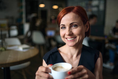 Portrait of attractive woman having sitting in a cafe, holding a cup of coffee. - HPIF18027