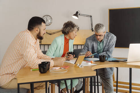 Geschäftsleute, die einen Online-Stream aufzeichnen und am Schreibtisch im Studio sitzen - EHAF00017