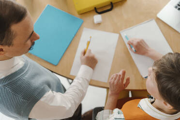 Colleagues standiung at desk talking taking notes on papers - EHAF00028