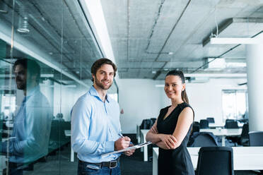 Young businesspeople with clipboard standing in an office, working. - HPIF18050