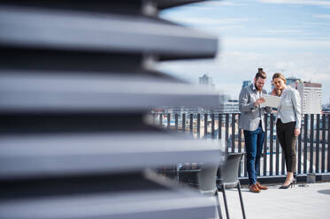 Zwei fröhliche junge Geschäftsleute mit Tablet stehen auf einer Terrasse vor einem Büro und arbeiten. - HPIF18145