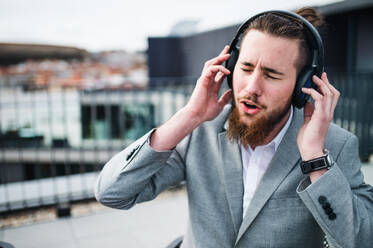 A young businessman with headphones sitting on a terrace, having fun. - HPIF18162