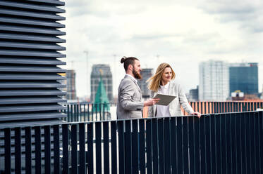Zwei fröhliche junge Geschäftsleute mit Tablet stehen auf einer Terrasse vor einem Büro und arbeiten. - HPIF18201