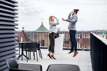 Zwei junge Geschäftsleute mit Tablet stehen auf einer Terrasse vor ihrem Büro und drücken ihre Begeisterung aus. - HPIF18208