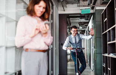 Young businessman with motor scooter in an office building, taking a break. - HPIF18261