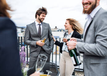 A midsection of group of joyful businesspeople having a party outdoors on roof terrace in city. - HPIF18264