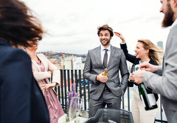 A large group of joyful businesspeople having a party outdoors on roof terrace in city. - HPIF18265