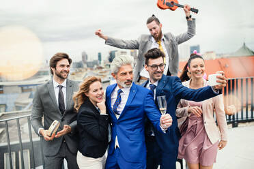 Eine große Gruppe fröhlicher Geschäftsleute feiert eine Party auf der Dachterrasse in der Stadt. - HPIF18268