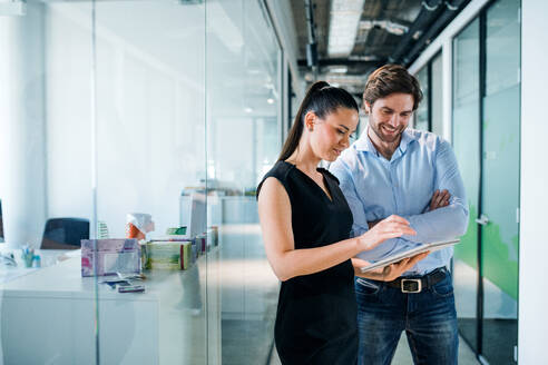 Young businesspeople with clipboard standing in an office, working. - HPIF18282