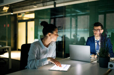 Two businesspeople with a computer sitting in an office at desk, working. - HPIF18301