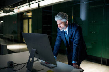Ein Porträt von reifen Geschäftsmann mit Computer in einem Büro, arbeiten. - HPIF18309