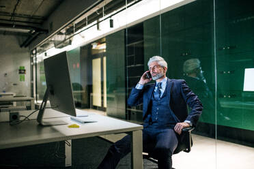 Ein Porträt eines reifen Geschäftsmannes mit Smartphone in einem Büro, der telefoniert. - HPIF18310